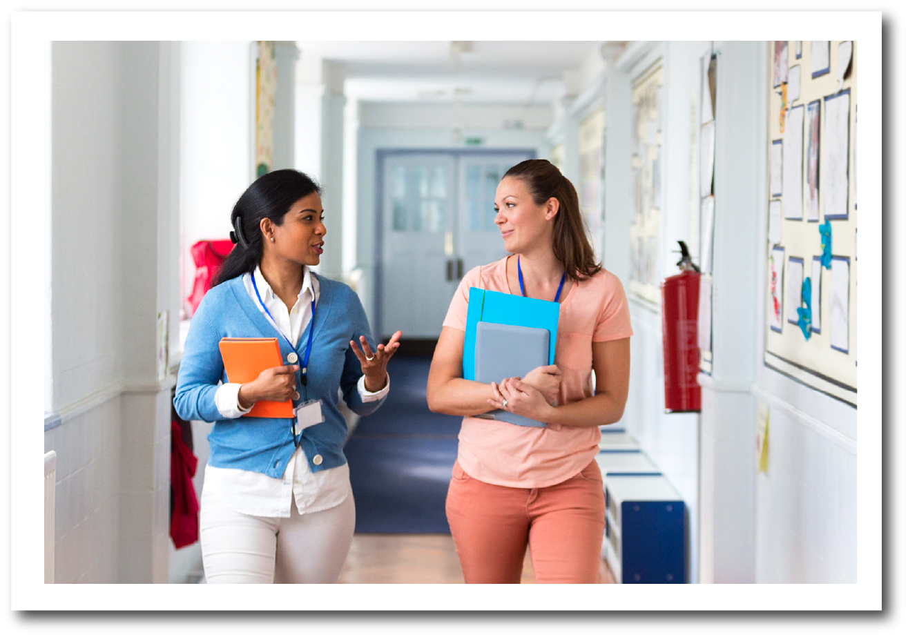 Two adults talking and walking down a hallway.