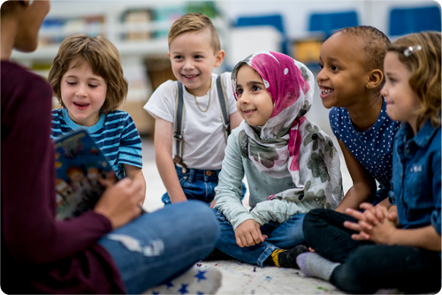 Teacher showing a book to elementary age students.
